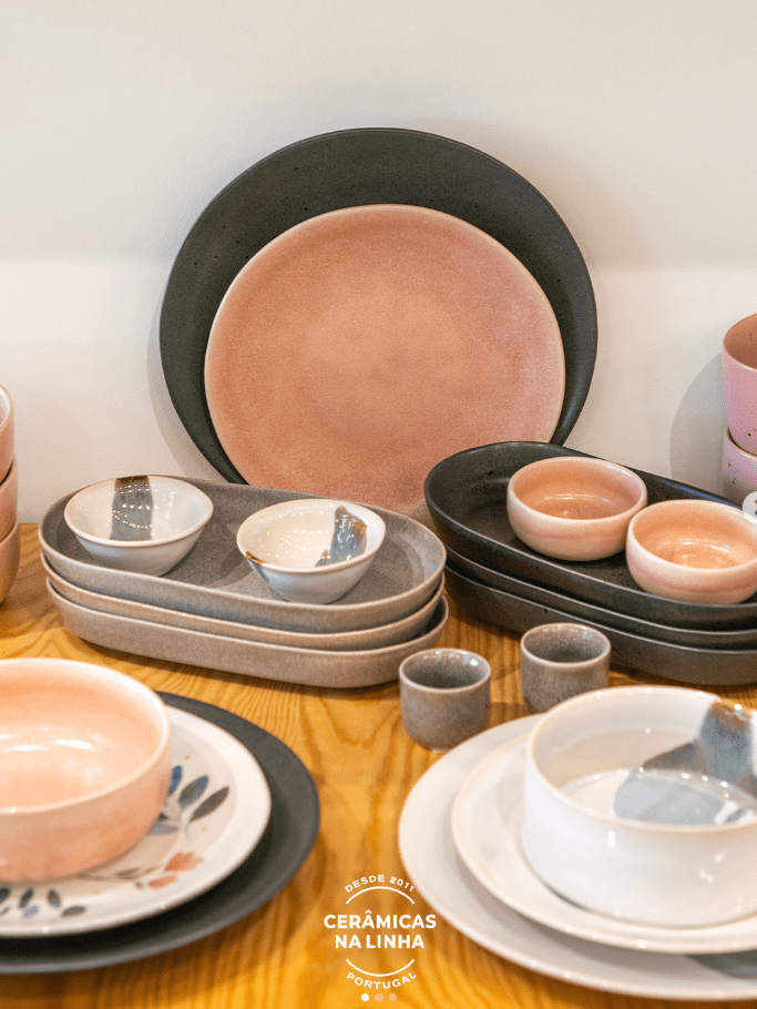 Elegant ceramic dishware in pink and gray tones displayed on a wooden table.