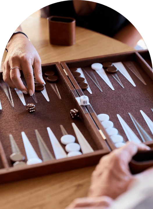 People playing backgammon with dice and checkers on a wooden board game.