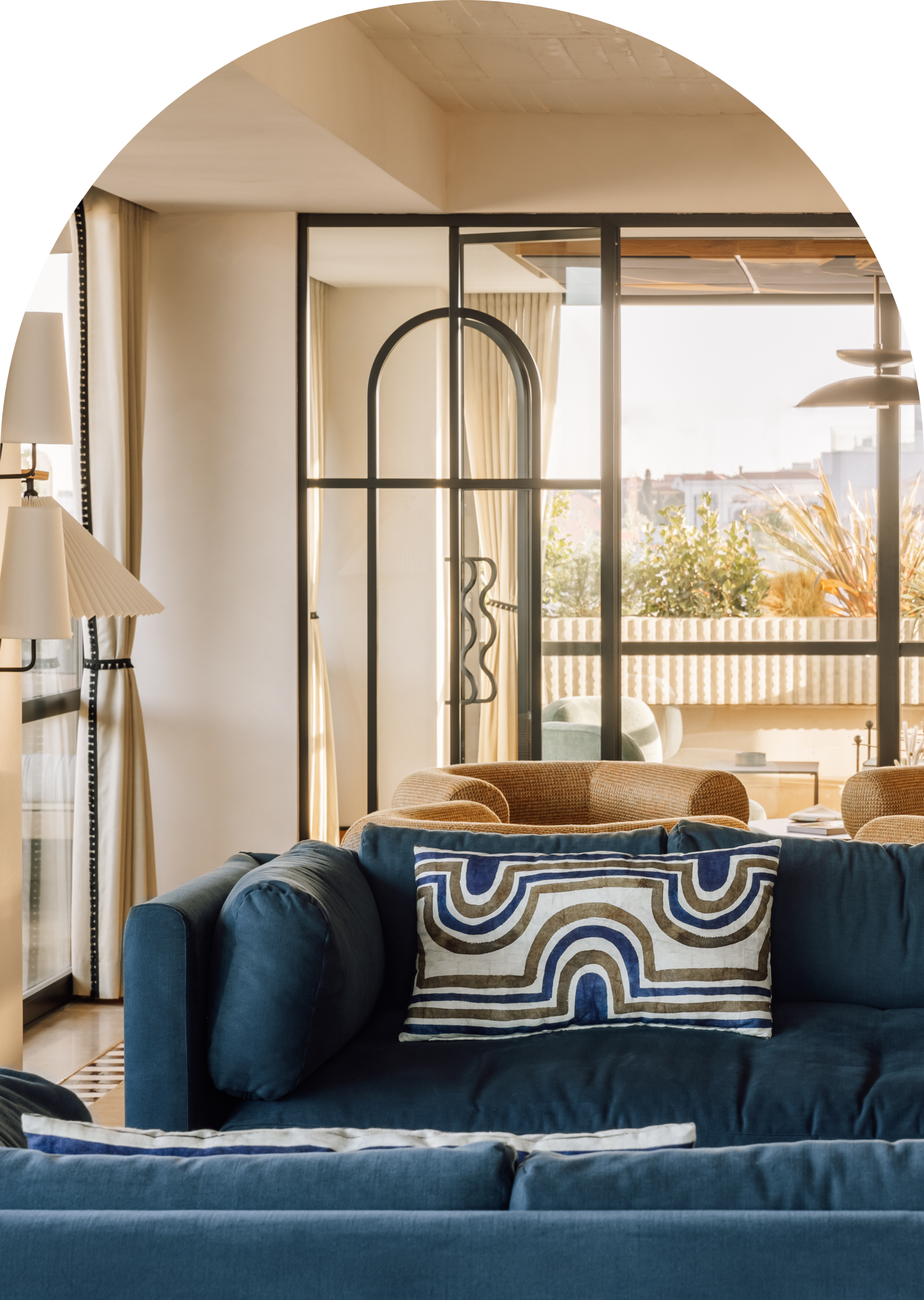 Stylish living room with blue couch, geometric pillow, and natural light from large windows. Modern interior design.