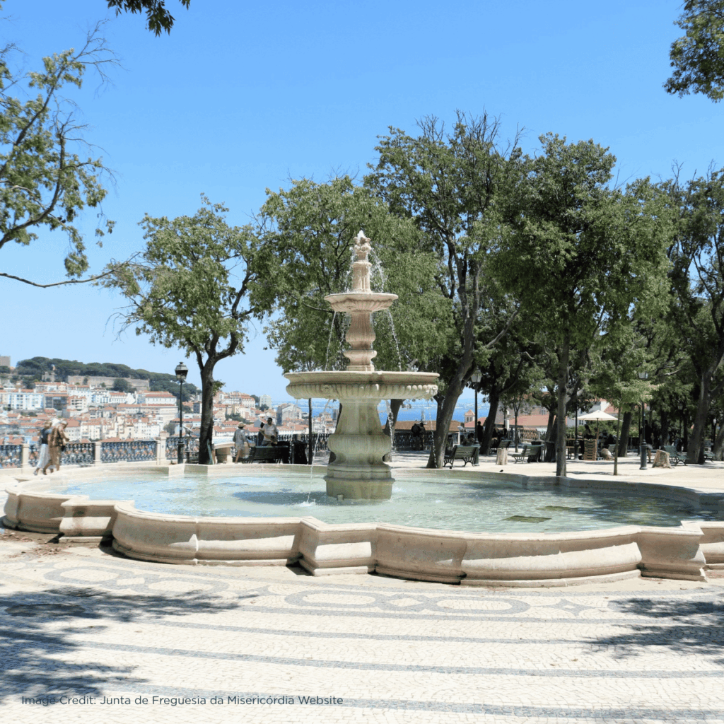 Scenic park with a decorative fountain surrounded by trees and city views on a sunny day in Lisbon.