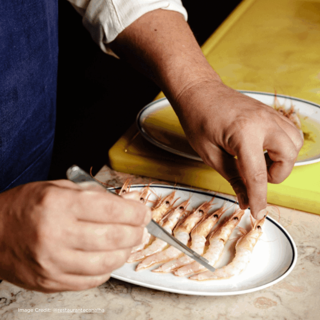 Chef expertly preparing fresh shrimp on a plate, showcasing culinary skills and fresh seafood presentation.