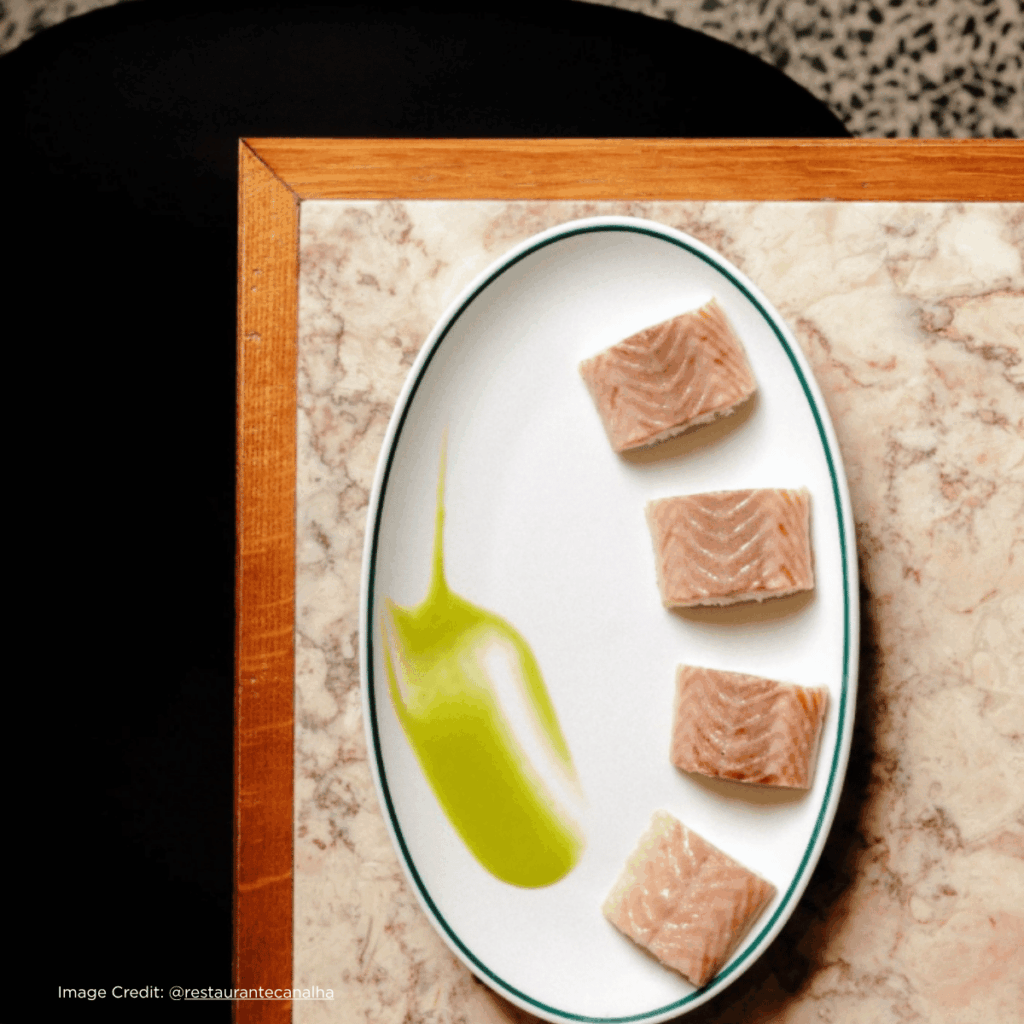 Deliciously plated salmon squares with a vibrant green sauce, set on a marbled countertop. Elegant food presentation.