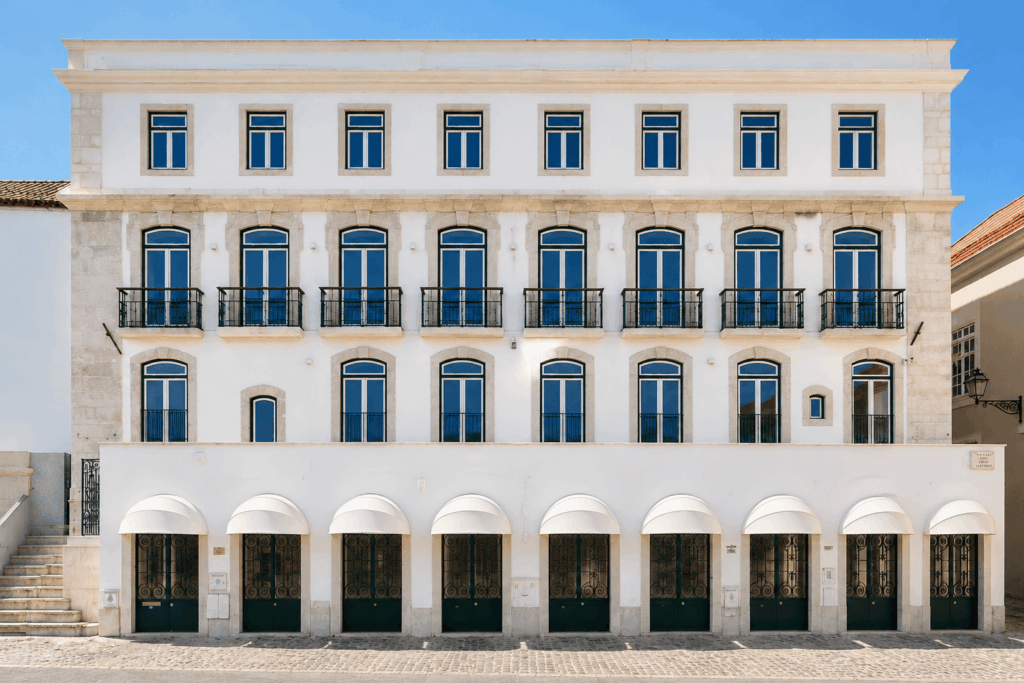 Elegant white building with large windows and balconies, showcasing classic architecture against a clear blue sky.