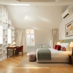 Modern bedroom with upholstered headboard, warm bedside lighting, and abstract artwork above the bed.