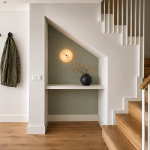 Modern entryway with a green accent wall, minimalist decor, a cozy coat rack, and stylish wooden staircase.