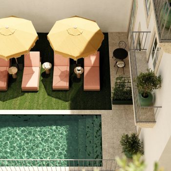 Aerial view of poolside lounge chairs and yellow umbrellas next to a clear swimming pool and balcony seating.