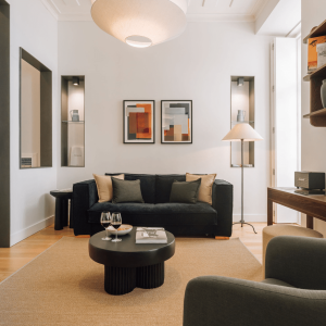 Modern living room with black sofa, abstract art, and warm lighting. Cozy seating and stylish decor elements.