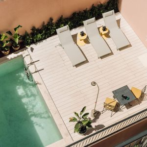 Outdoor terrace with swimming pool, sun loungers, and seating area surrounded by plants.
