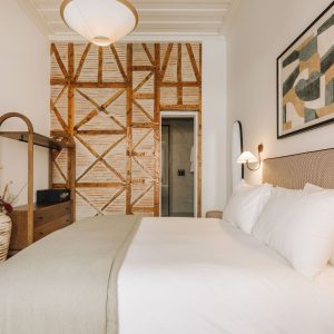 Elegant bedroom with textured headboard, warm lighting, and decorative wooden wall feature.