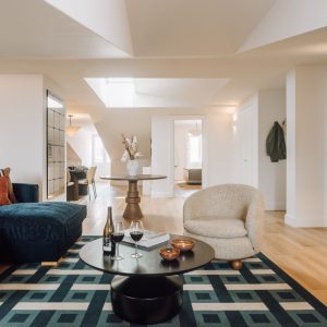 Bright open-plan living space with velvet sofa, modern kitchen, dining area, and skylight creating a spacious atmosphere.