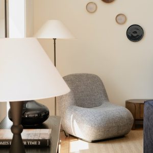 Cozy modern living room with gray armchair, stylish lamps, and decorative wall plates.